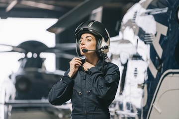 Pilot girl poses with her helicopter wearing helmet