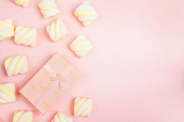 Pink gift box with colorful spiral marshmallows on pink background. Copy space.