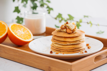Stack of delicious pancakes with chocolate, honey, nuts and slices of banana on plate on stone background