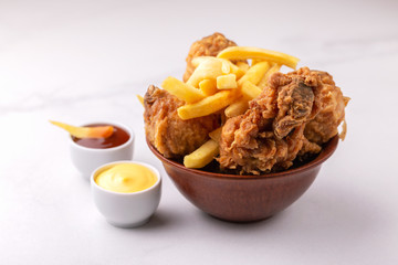 Crispy chicken legs and french fries potatoes. Fast junk food