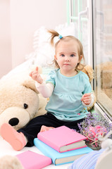 little girl near the window with books