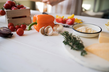 Cheese with fresh vegetables basil and cutting board on white, shabby, rustic kitchen table. Ingredients for cooking on the vintage rural kitchen. Healthy traditional food. Selective focus. Free space