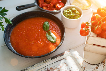 Italian food background. Traditional Italian cooking with tagliatelli pasta, tomatoes, basil, cheese and pesto on rustic wood table in the summer sun's rays. Organic food. Natural nutrition.