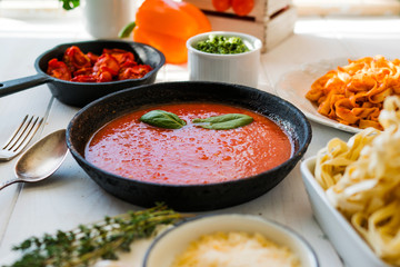 Italian food cooking concept. Ingredients for preparation pasta. Tomato, olive oil, spices, herbs, cheese, tomato sauce on a weathered wooden table indoors illuminated by the summer sun. Healthy food.