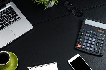 Top view, black desk with computer graph, magnifier and calculator