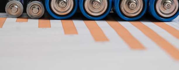 Energy concept. Ordinary battery on paper surface with business chart