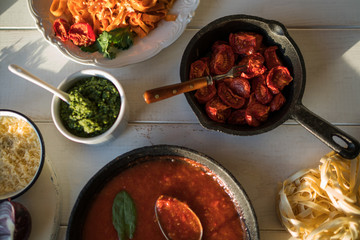 Products for cooking. Tomato sauce, pasta, tomatoes, garlic, olive oil on the old wooden background. Plate of pasta with tomato sauce with ingredients for cooking on white background, top view.
