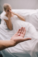 cropped shot of man with pills in hand and pregnant woman feeling discomfort at home