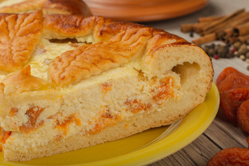Cut homemade curd cake on a wooden background with ingredients.