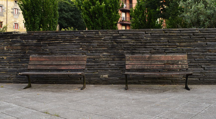 Bancos de madera sobre muro de piedra.