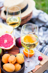 Picnic background with white wine and summer fruits on green grass, summertime party