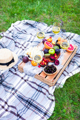 Picnic background with white wine and summer fruits on green grass, summertime party