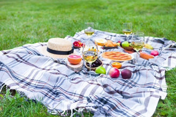 Picnic background with white wine and summer fruits on green grass, summertime party