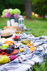 Picnic background with white wine and summer fruits on green grass, summertime party