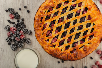 Berry pie on a wooden background with ingredients.