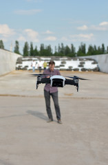 Man holds remote controller with his hands while copter is flying on background. Drone hovers behind the pilot on farm. No face. Agricultural new technologies and innovations concept.