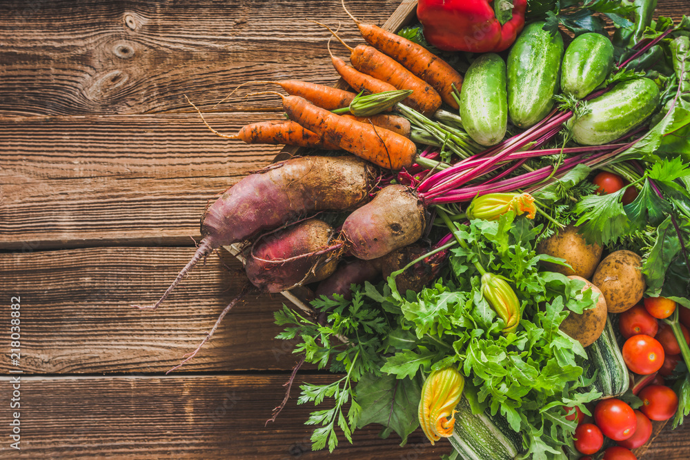 Wall mural Assortment of fresh organic vegetables harvested in the garden. Bio produce on farmer market, vegetable box on wooden background