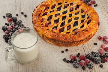 Berry pie on a wooden background with ingredients.