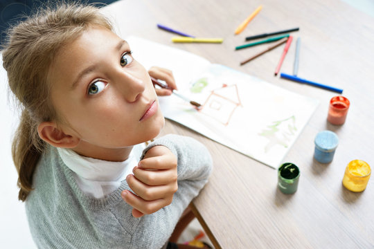 Lonely girl is drawing. Photo of cute schoolgirl doing homework. Education concept