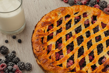 Berry pie on a wooden background with ingredients.