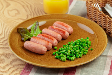 Fried sausages with green peas breakfast dish close up