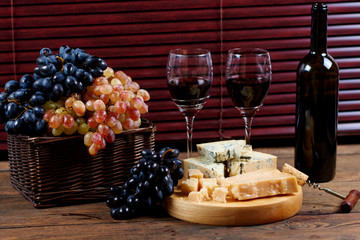 Tasty gorgonzola cheese lying on board for red dry chardonnay in glasses.Wine degustation with...