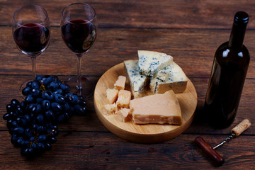 Corkscrew for opening bottle of soft alcohol drink lying on wooden vintage table with colorful fruit, tasty gorgonzola and glasses for dinner.