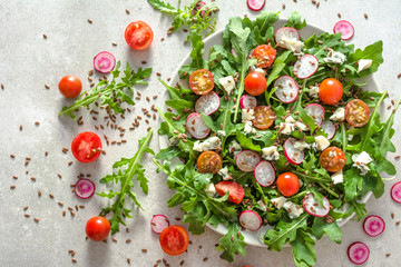 Fresh salad with with arugula and vegetables on plate, top view