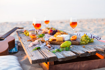 Pique-nique sur la plage au coucher du soleil dans un style bohème. Dîner romantique, fête d& 39 amis, été, concept de nourriture et de boisson
