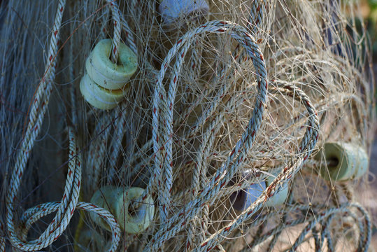 Fishing nets hang outdoor, drying in the sun. Vintage fishing nets for design about a marine life or craft of fishermen in retro style.  Fishing equipment and old tackle as texture.