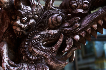 Traditional wooden sculpture art and culture. Ancient wooden carving. Vintage dragon. Close up of a brown dragon carving amidst beautiful decorations Chinese buddhist temples. Selective focus.
