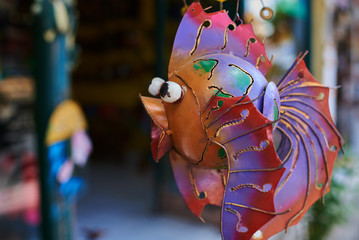 Colorful  souvenir background. Hanging decoration in the market. Handmade metallic fish hanging on...