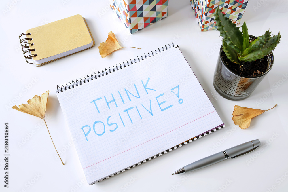 Poster think positive written in a notebook on white table