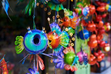 Colorful  souvenir background. Hanging decoration in the market. Handmade metallic fish hanging on...