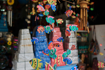 Souvenir background. Hanging decoration in the market. Handmade colorful  wooden carved  hanging on the tourist market. Sale of souvenirs. Fishes with bright colorful patterned. Selective focus.