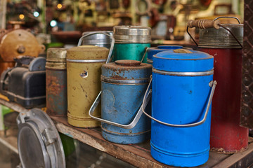 Naklejka premium Many used thermos bottle. Retro equipment. Various objects for sale at a indoor flea market. View of a display full of interesting old things for sale. Vintage assorted second-hand objects.
