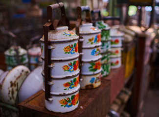 Old, vintage kitchenware. Retro equipment of cooking. Various objects for sale at a indoor flea market. View of a display full of interesting old things for sale. Vintage assorted second-hand objects.