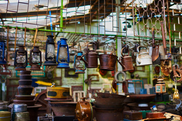 Vintage lamps. Various vintage objects for sale at a indoor flea market. View of a display full of interesting old things for sale. Many groups of vintage assorted second-hand objects.