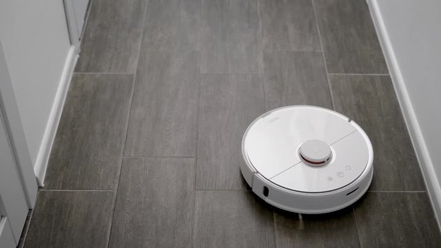 robot cleaner is moving over floor in a modern apartment, working in self-drive mode, cleaning autonomously