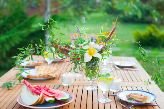 Family outdoor dinner in the garden in summer at sunset. Picnic food and drink concept