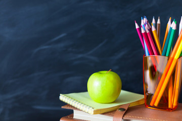 Naklejka premium Back to School cocept. Still life with school books, pencils and apple against blackboard background