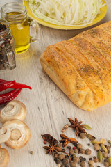 Pie with cabbage and mushrooms on a wooden background with ingredients.
