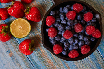Colorful mix of seasonal fruits lying on wooden table.Different tasty berries in frying pan....