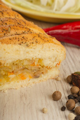 Pie with cabbage and mushrooms on a wooden background with ingredients.