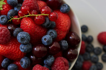 Bowl of healthy fresh mixed berries on wooden background. Top view.