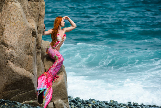 Beautiful mermaid with long tail on sea shore