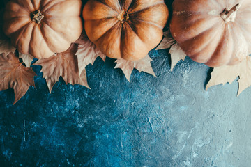 Pumpkins and maple leaves on a blue stone background, retro style, Thanksgiving, harvesting, postcard, copy space