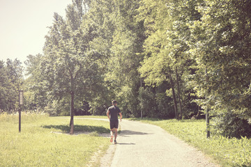 back view of running man at park, training in the nature
