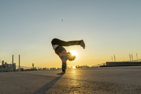 Acrobat doing handstand in the city at sunrise