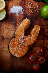 Big salmon steak cooking at home, watered lemon, served it with a salad of fresh tomatoes, Fuming just pulling out of the oven a piece of salmon